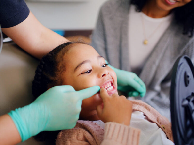 Child, consultation and dentist with mirror in office for dental checkup, show cavity and hygiene. Mother, kid and pediatric for oral health, teeth whitening and inspection for cleaning service